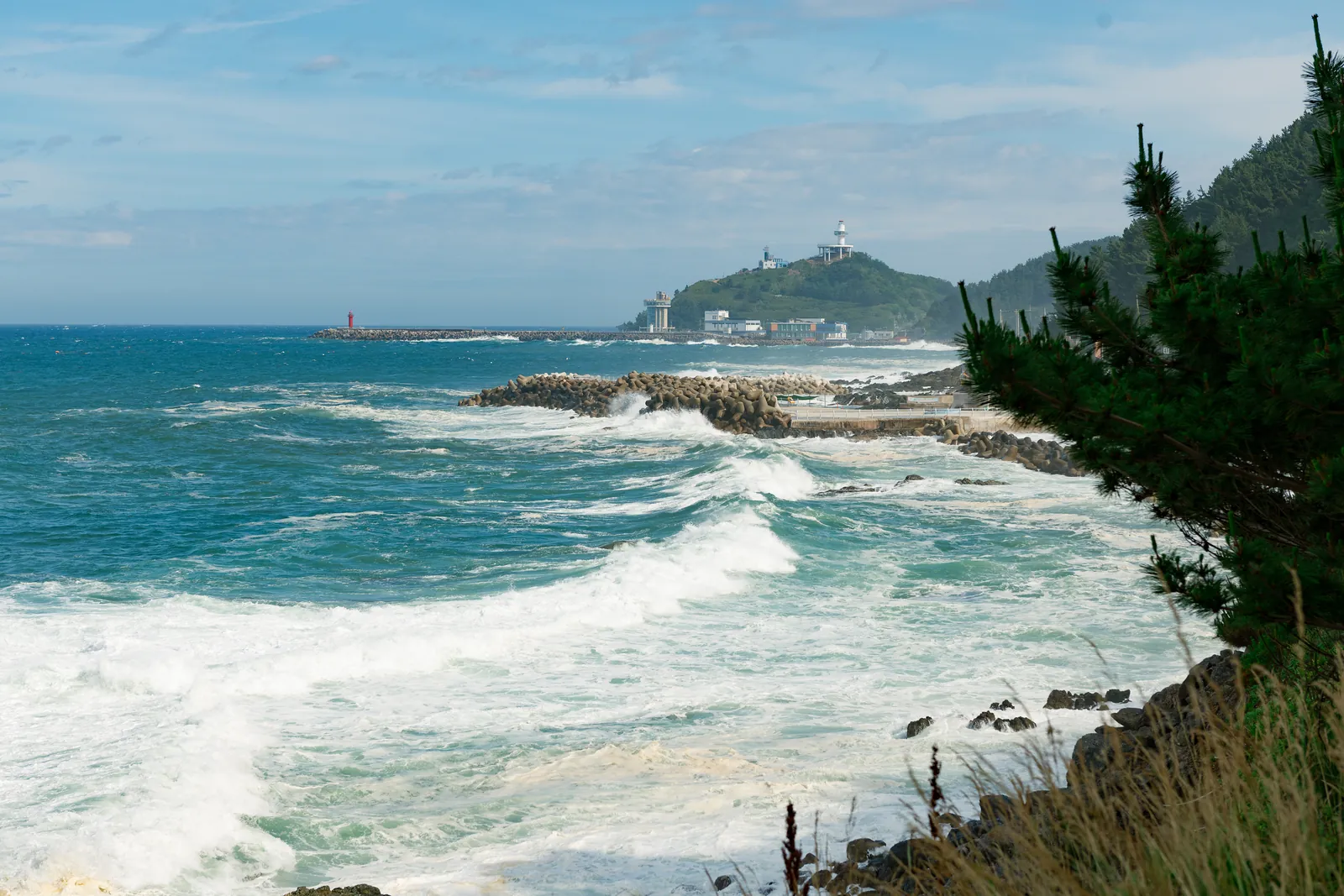 Waves breaking on a rocky shore, a lighthouse in the distance